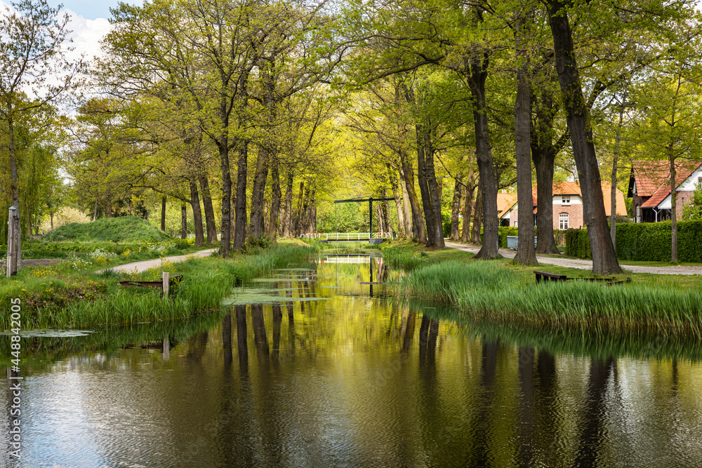 Canal with water surrounded by grass, greenery and nature on a calm picturesque dutch rural countryside in Grientsveen, The Netherlands on a sunny day during spring Canal with water surrounded by grass, greenery and nature on a calm picturesque dutch rural countryside in Grientsveen, The Netherlands on a sunny day during spring