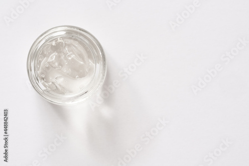 Aloe vera gel in a glass glass jar on white background, top view. Healthy cosmetic product.