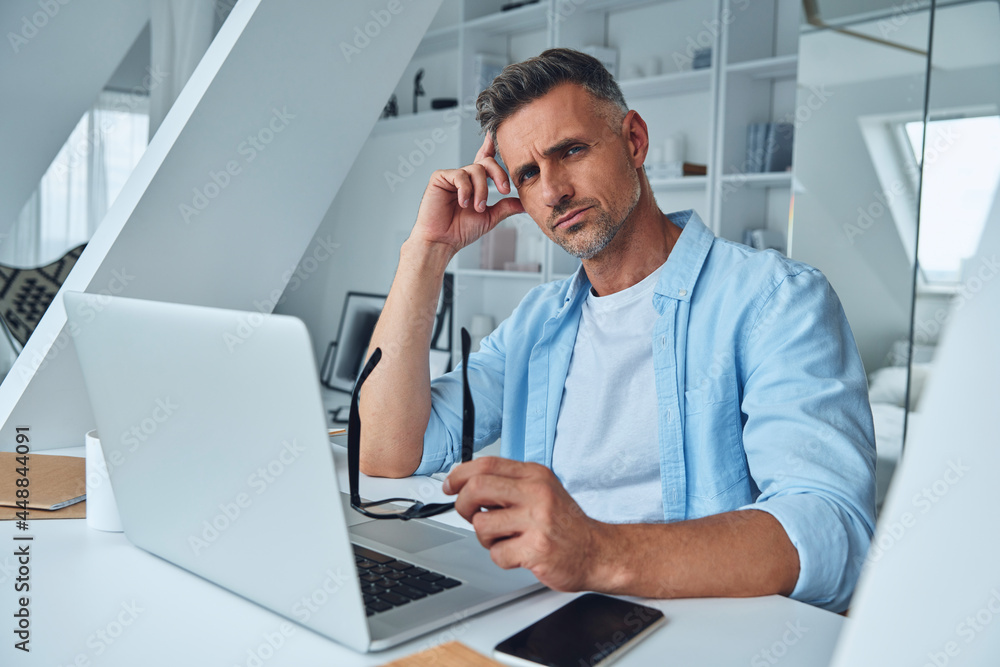 Confident mature man looking at camera while sitting at the office desk Confident mature man looking at camera while sitting at the office desk