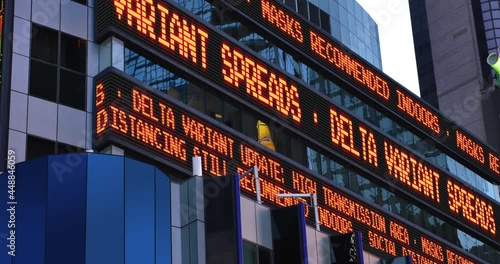 A fictional stock market ticker informs pedestrians about the Delta Variant strain. Masks and social distancing were common practices to slow down the spread of COVID-19 during the pandemic of 2021.   photo