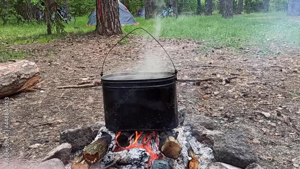 Cooking while hiking on a campfire, in the forest. A pot in the flame Cooking while hiking on a campfire, in the forest. A pot in the flame