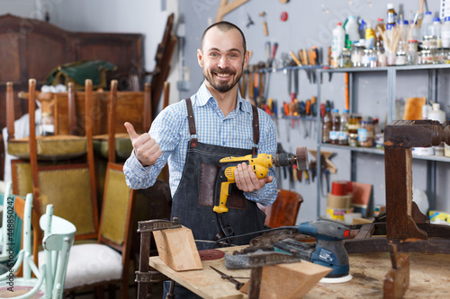 Experienced craftsman repairing antique furniture in workshop using tools
