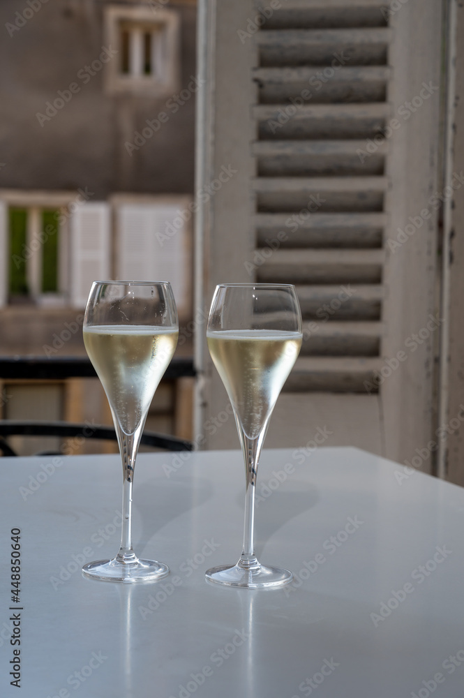 Romantic party with two glasses of white cold champagne and view on old street in French village