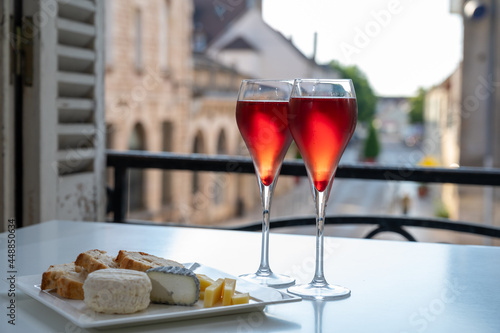 Drinking of Kir Royal,  French aperitif cocktail made  from creme de cassis topped with champagne, typically served in flute glass, with view on old French village photo