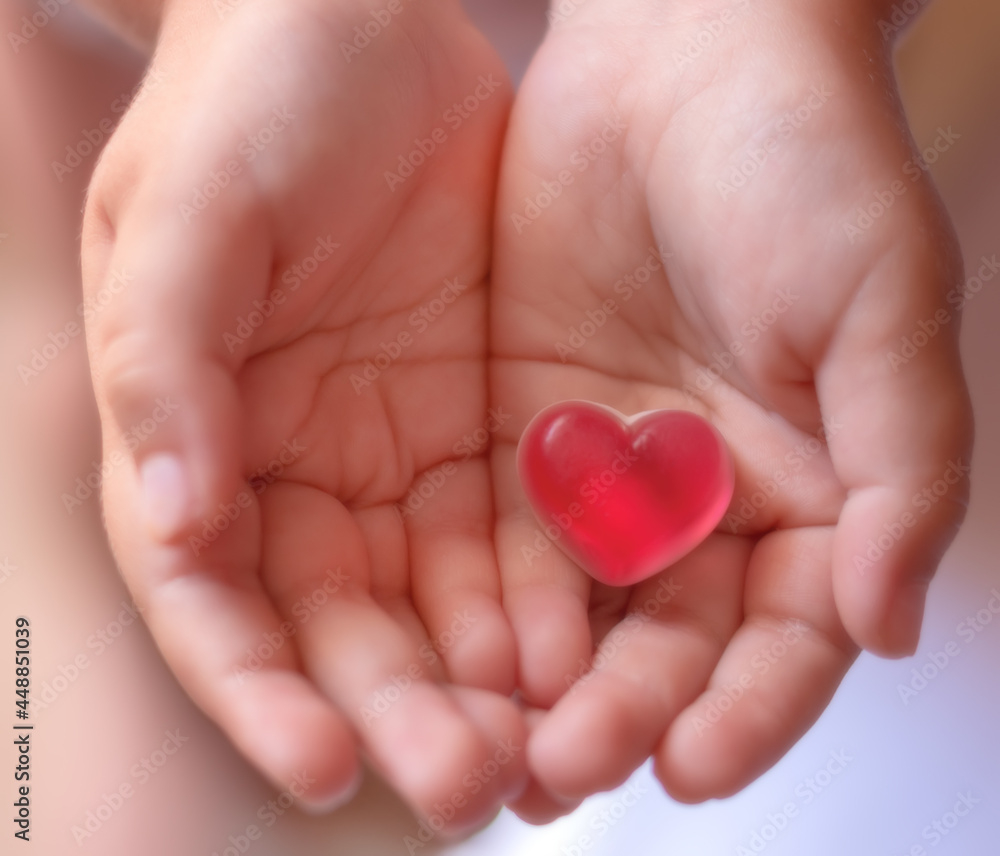 Candy in the shape of a heart, in children's palms Candy in the shape of a heart, in children's palms