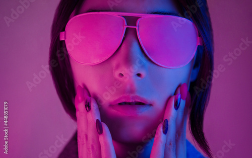 Portrait of a young woman in neon light with a surprised expression on her face.