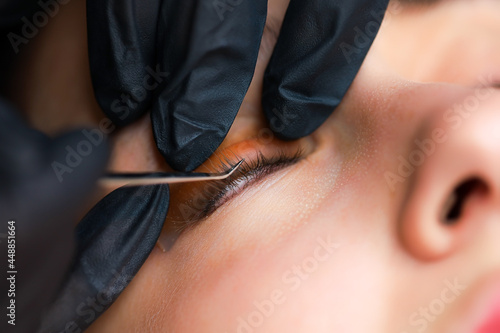 the hands of the master close up correct the eyelash glued to the roller with special tweezers