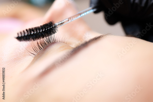 the hands of the master of lamination of eyelashes are combed with a brush the finished result is lamination of cilia photo