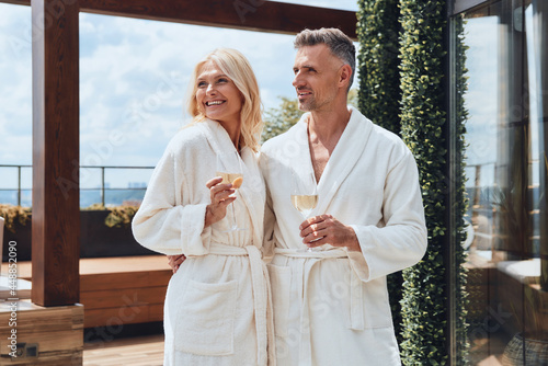 Canvas Print Beautiful mature couple in bathrobes enjoying champagne while relaxing in luxury
