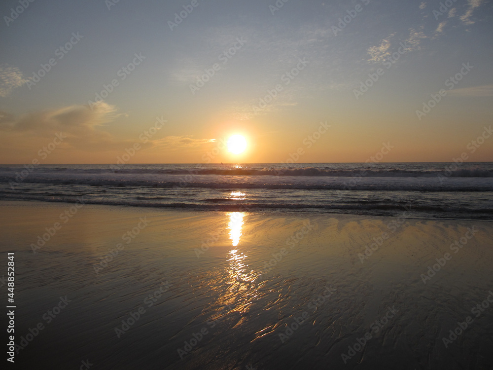 Sunset over ocean waves as they reach the beach