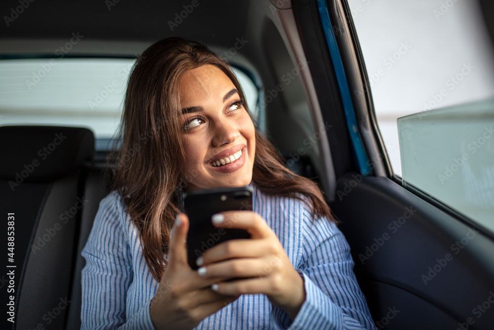 Businesswoman sitting on back seat of a car and looking outside the window. Female business executive travelling by a cab. Cropped shot of an attractive young woman sitting in the backseat of a car Businesswoman sitting on back seat of a car and looking outside the window. Female business executive travelling by a cab. Cropped shot of an attractive young woman sitting in the backseat of a car