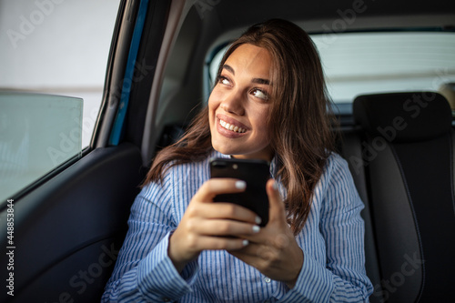 Businesswoman sitting on back seat of a car and looking outside the window. Female business executive travelling by a cab. Cropped shot of an attractive young woman sitting in the backseat of a car