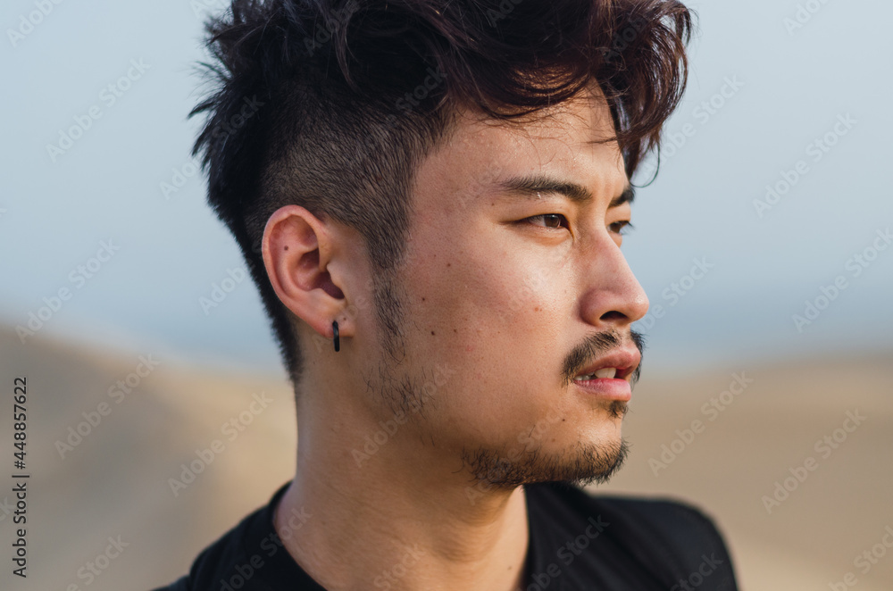 Fototapeta premium Portrait of young handsome Chinese tourist standing while admiring the sand dunes in Maspalomas