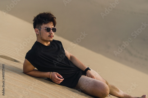Portrait of young handsome Chinese tourist laying while admiring the sand dunes in Maspalomas