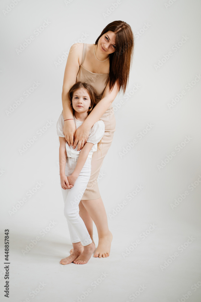 Mom and daughter pose in a white photo studio. Mom and daughter pose in a white photo studio.