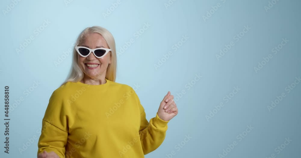 Happy mature woman dancing against color background Happy mature woman dancing against color background