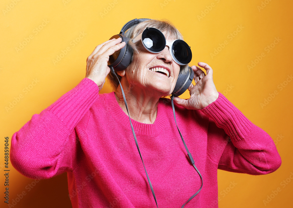 Cheerful elderly woman listening to music with headphones over white background