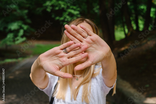 Girl covers her face with hand stop gesture. Negative defensive concept of communication psychology. Woman rejects offer and shows hold sign