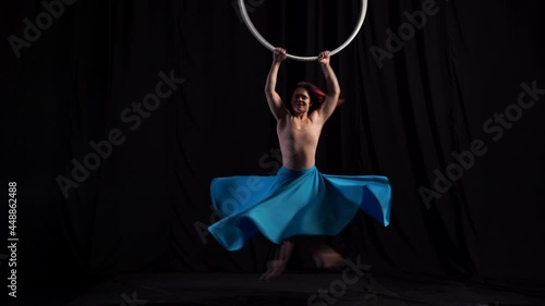 Professional circus performer spins very quickly on the aerial hoop in a beautiful blue flower-shaped skirt