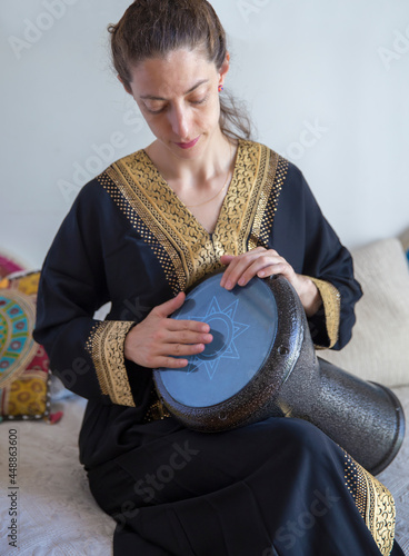 Female drummer wearing a traditional arabic clothes playing darbuka percussion instrument. photo