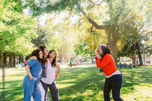 Happy girlfriends taking selfie on photo camera in park