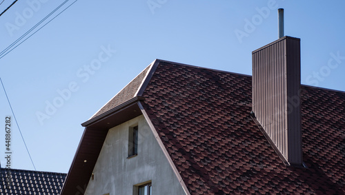 Brown corrugated metal profile roof installed on a modern house. The roof of corrugated sheet. Roofing of metal profile wavy shape. Modern roof made of metal. Metal roofing.