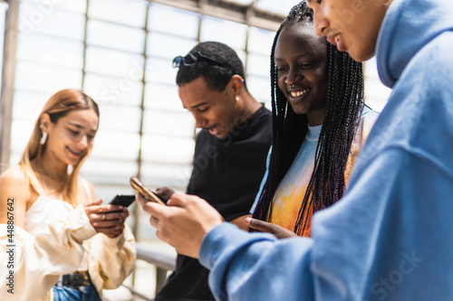 Multiracial friends browsing smartphones on street photo