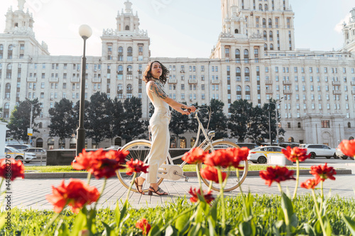 Young woman with bicycle standing on city square photo