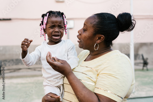 Black mother comforting crying daughter on street