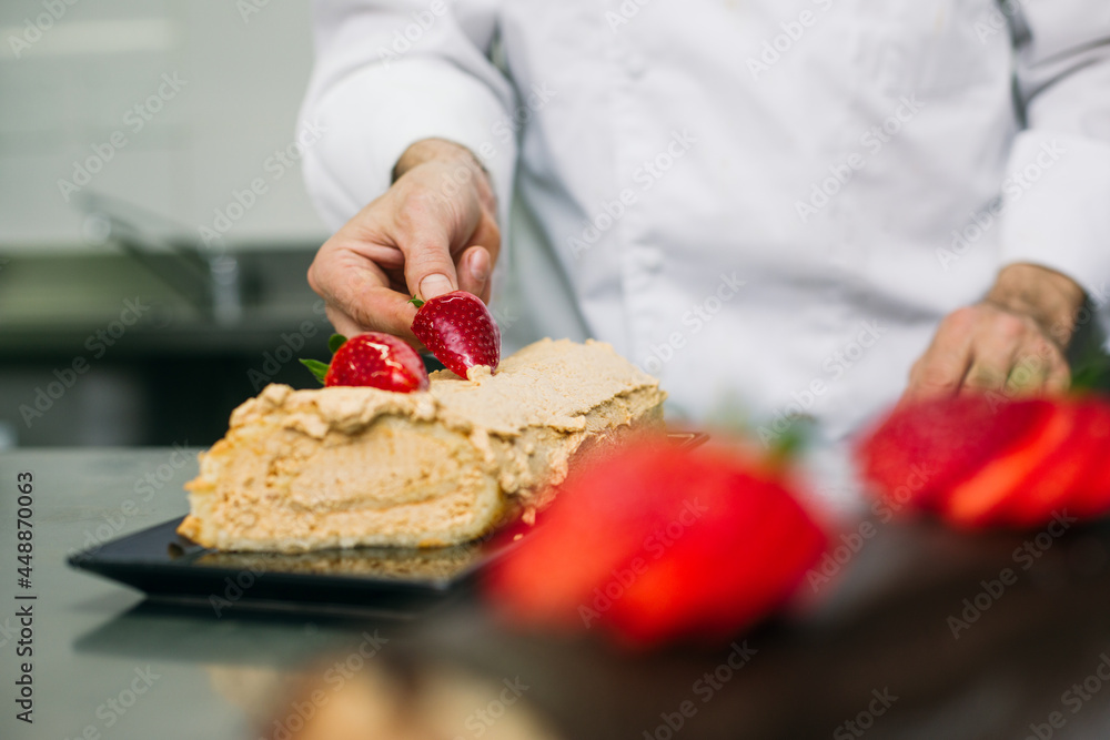 Chef decorating cake with strawberries Chef decorating cake with strawberries