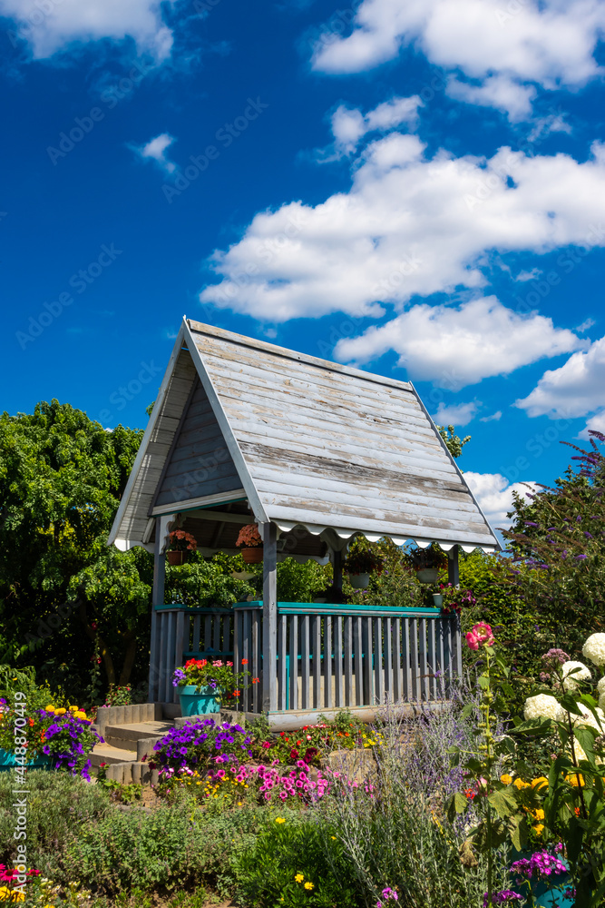 Wooden garden gazebo in the garden full of flowers. Photo taken at noon in perfect lighting conditions