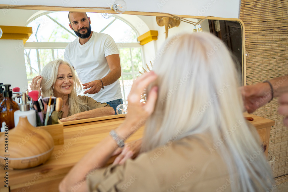 Woman looking her hairstyle at mirror Woman looking her hairstyle at mirror