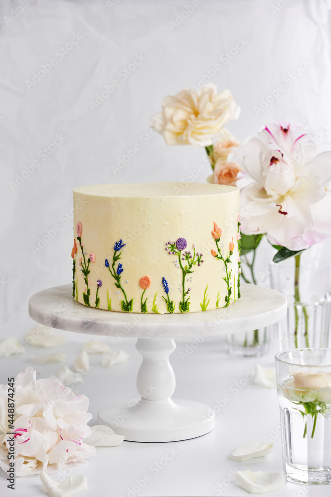 Delicious wedding cake on stand on table with flowers Delicious wedding cake on stand on table with flowers