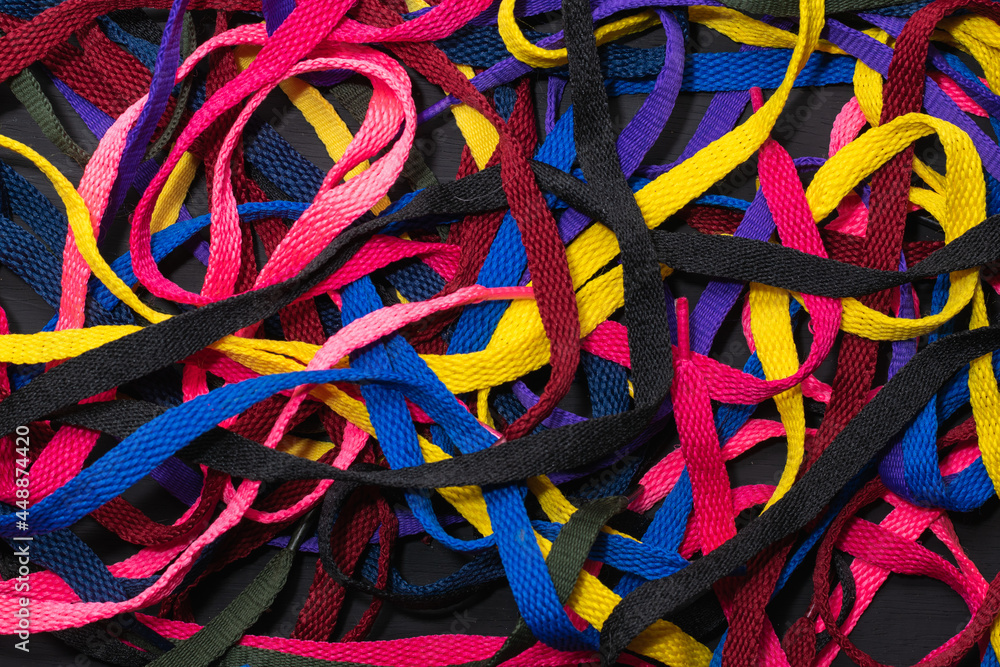 colorful shoelaces background, on black wood, messy, clutter concept, advertisement