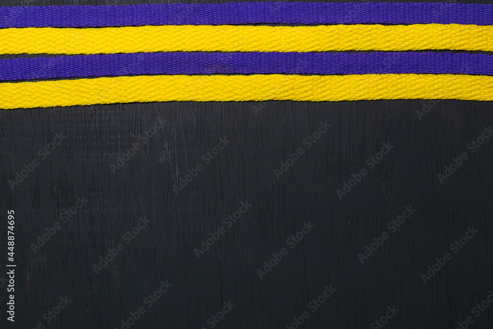 yellow and purple shoelaces, lakers flag, on black wooden background, leaving space for advertising text yellow and purple shoelaces, lakers flag, on black wooden background, leaving space for advertising text
