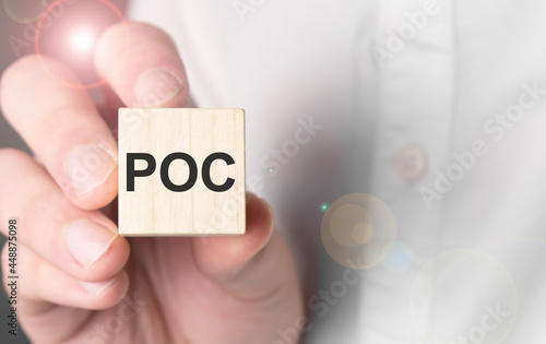 Man holding poc word on wooden cube. photo