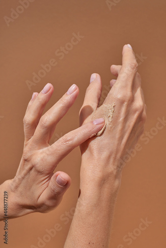 Unrecognizable female smearing scrub on hand photo