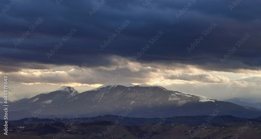 Nuvole tempestose sopra le montagne  e raggi di sole al tramonto