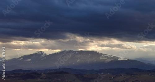 Nuvole tempestose sopra le montagne  e raggi di sole al tramonto © GjGj