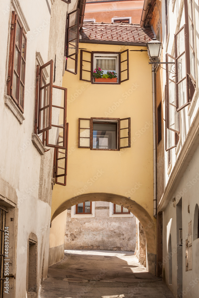 Empty picturesque medieval narow street with a bridge house over an arcade in the historical center of Skofja Loka, in Slovenia, in a district dating back from the middle ages...