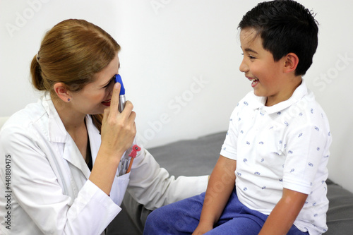 Female professional pediatrician doctor working checking a happy latin child 