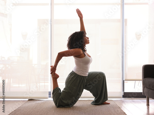 Calm black woman doing Anjaneyasana on rug photo