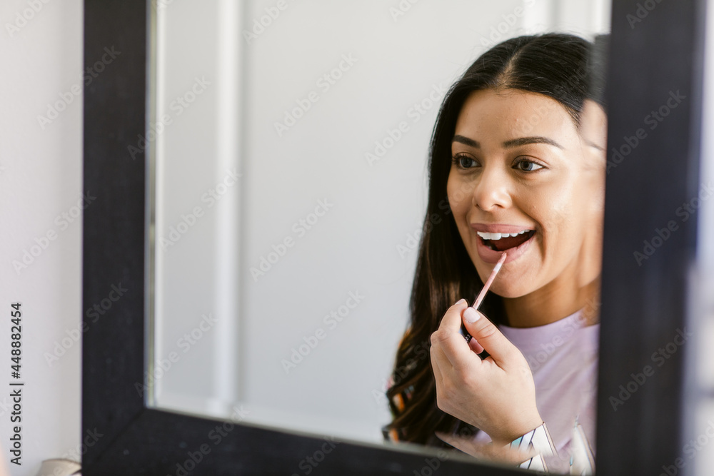 Happy woman applying lipstick during makeup procedure at home Happy woman applying lipstick during makeup procedure at home