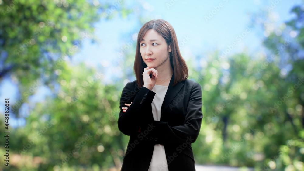 木々の前に立つビジネスウーマン