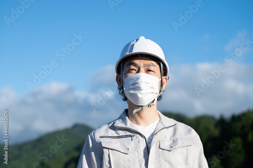 コロナ対応でマスクをする作業着の男性 見上げる コピースペースあり