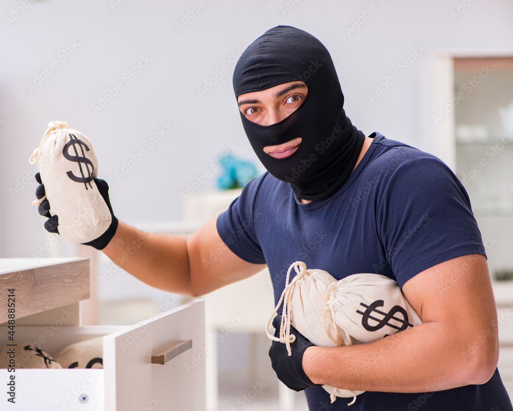 Robber wearing balaclava stealing valuable things Robber wearing balaclava stealing valuable things