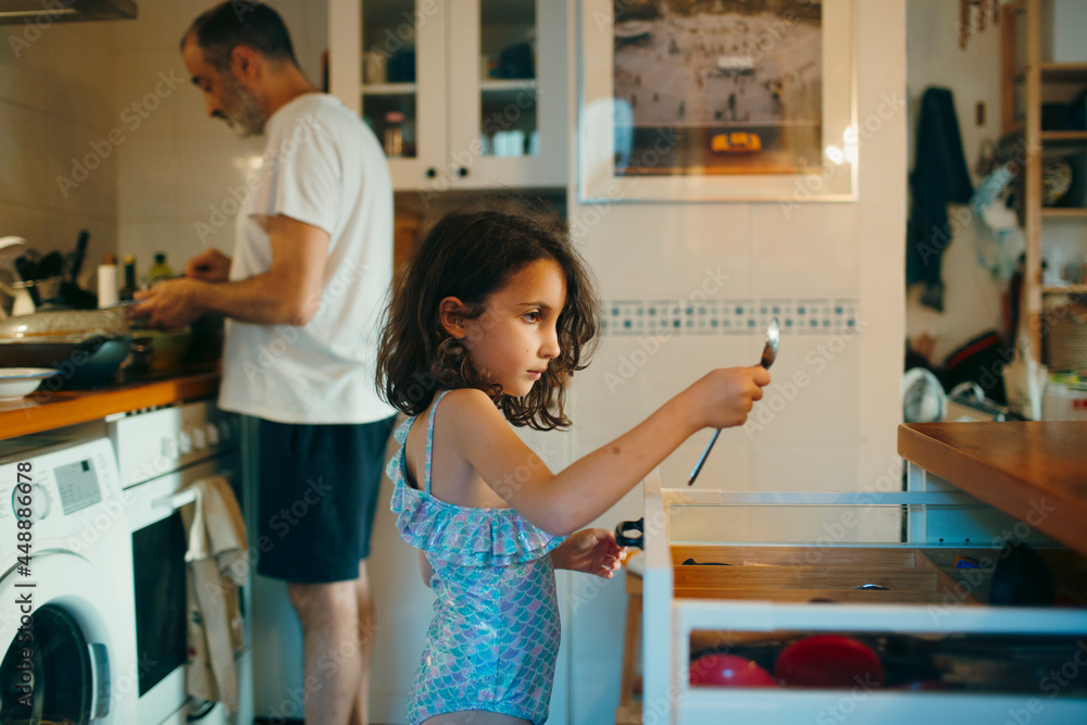 7-year old kid helping her dad in home kitchen 7-year old kid helping her dad in home kitchen