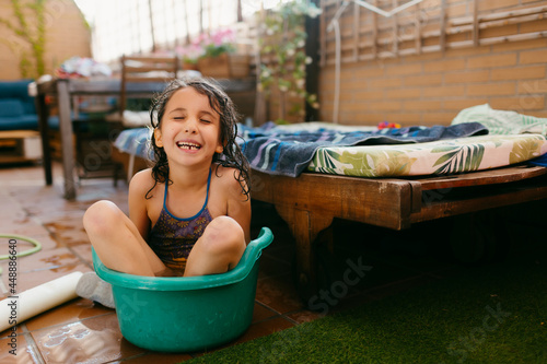 Kid inside a washbowl in a terrace laughing