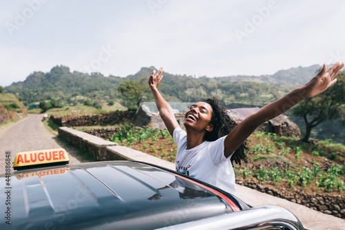 Happy ethnic female leaning out of car photo