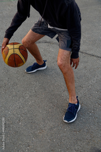 Crop sportsman dibbling basketball ball photo